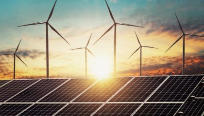 solar PV panels and wind turbines against setting sun in sky